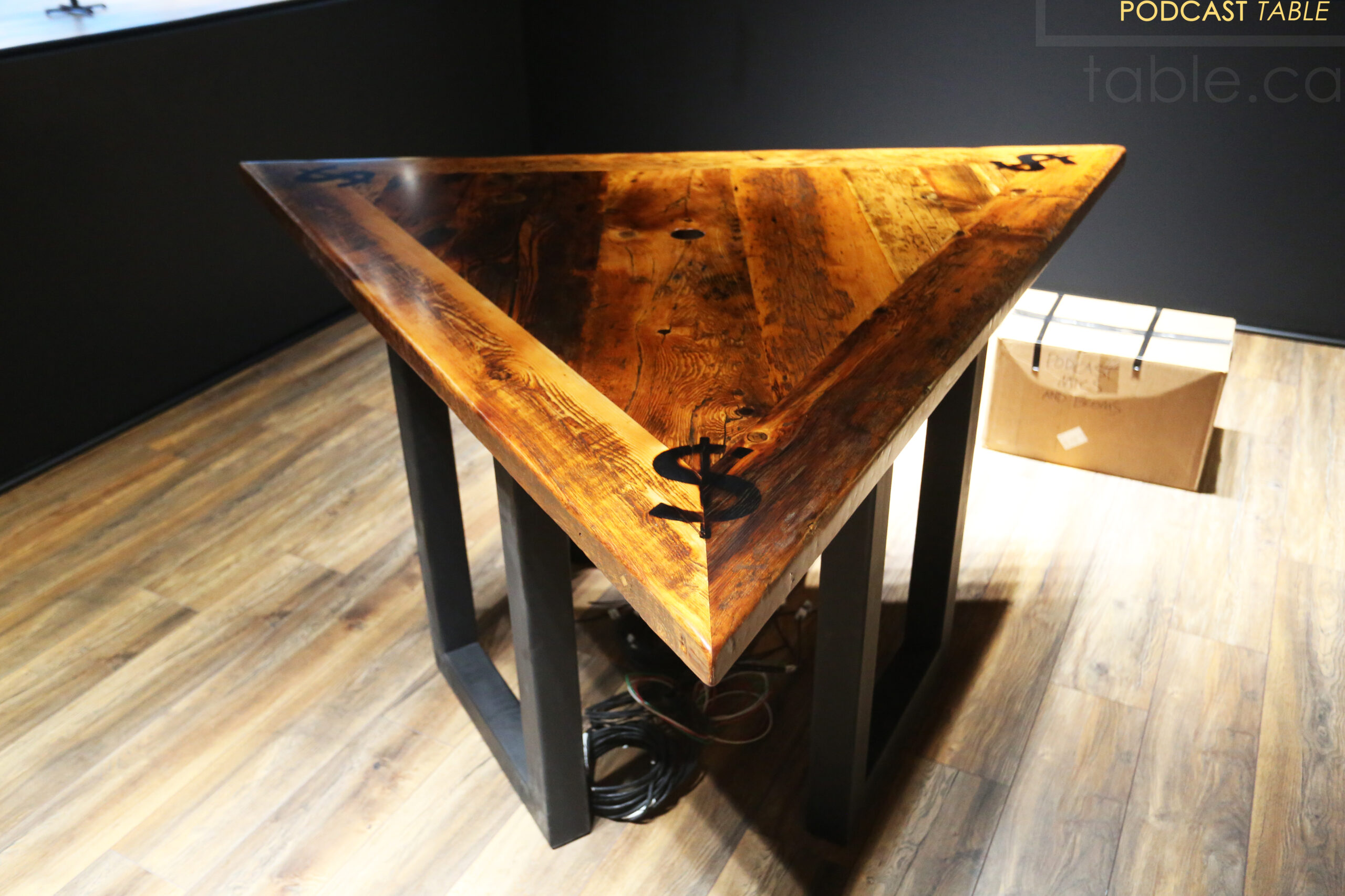 Project Summary: 6’ Per Side Triangle Reclaimed Ontario Barnwood Podcast Table - Made for a Burlington, Ontario home – 36” height – 3 Metal U Shaped Posts - Mitred Corners - Old Growth Hemlock Threshing Floor Construction - Original edges & distressing maintained - Premium epoxy + satin polyurethane finish – Centre Grommet Hole for Electronics - Custom Logo Brand Burn Embedded - www.table.ca